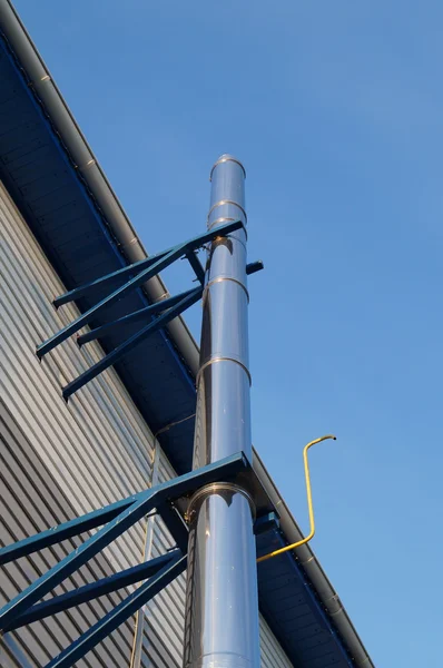 Brilliant pipe chimney attached to the building against the blue sky — Stock Photo, Image