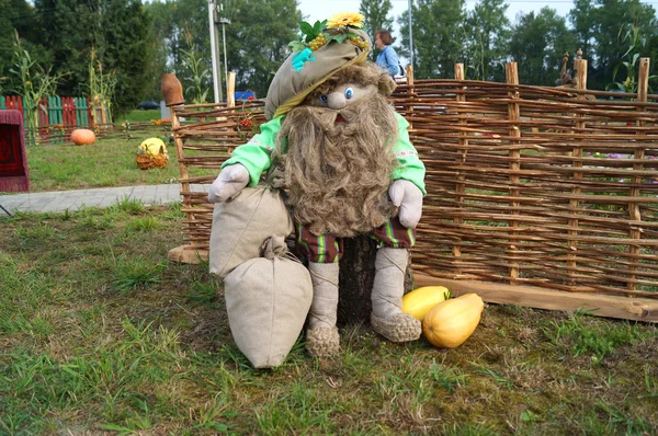 The composition of the dolls. Country muzhichek with a beard sitting near wicker fence