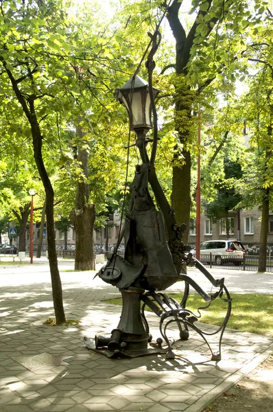 Stadens ljus i form av en abstrakt skulptur av en kvinna som sitter på en bänk — Stockfoto