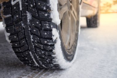 Karlı yolda kış çivili lastikler. Kış yolunda duran arabanın tekerlekleri. Sabah güneş ışığı.
