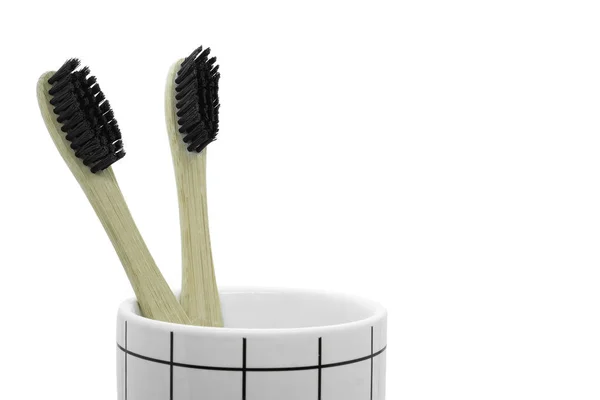 Dois bambu escova de dentes cerda preta em copo isolado no fundo branco. — Fotografia de Stock