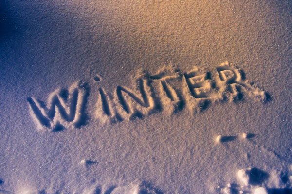 Text zima na sněhu textury v noci zesvětlit v teplém oranžovém světle. — Stock fotografie