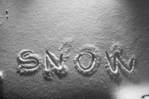 Text SNOW na sněhové ploše. Zimní sezóna a sněžení koncept. Vysoký kontrast černobílý obrázek. — Stock fotografie