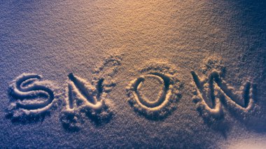 Geceleyin kar yüzeyinde kar yazısını yaz. Sıcak turuncu ışıkla aydınlat..