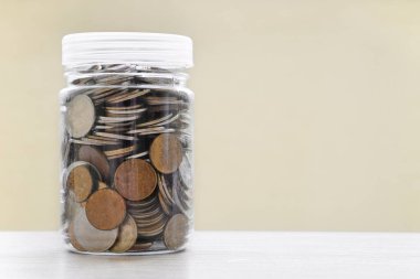 Masanın üzerinde bozuk paralarla dolu bir kavanoz. Biriktirme, para biriktirme kavramı. Boşluğu kopyala.