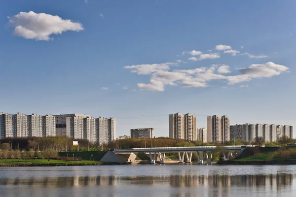 Спокойный городской город в летний день. Вид на озеро, парк, автомобильный мост, жилые дома и голубое небо с облаками. — стоковое фото