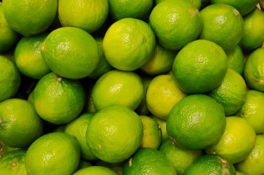 Piyasa tezgahında taze yeşil limon yığını. Gıda geçmişi ve limon hasat konsepti. Citrus arkaplanı.