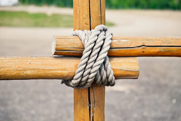 Close-up fragment of wooden fence. Wooden logs tied with strong rope. — Stock Photo, Image