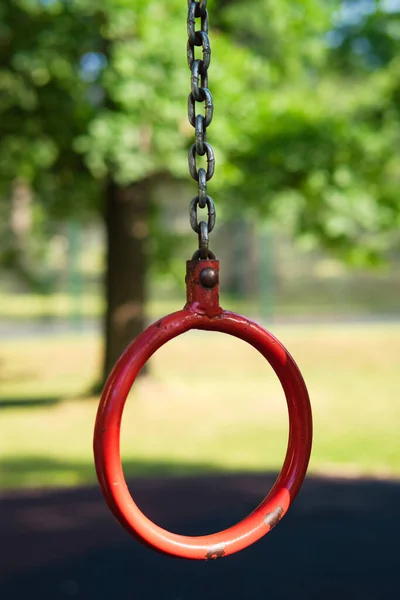 Güneşli yaz gününde zincirde asılı duran kırmızı demir yüzük. Çocuklar oyun bahçesinde. — Stok fotoğraf