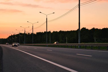 Arabalar akşam yolunda ilerliyor. Altın gün batımında yolculuk.