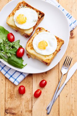 croque madame ahşap masa üstünde salata ile