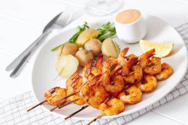 Grilled shrimp on skewer with potatoes and sauce clipart