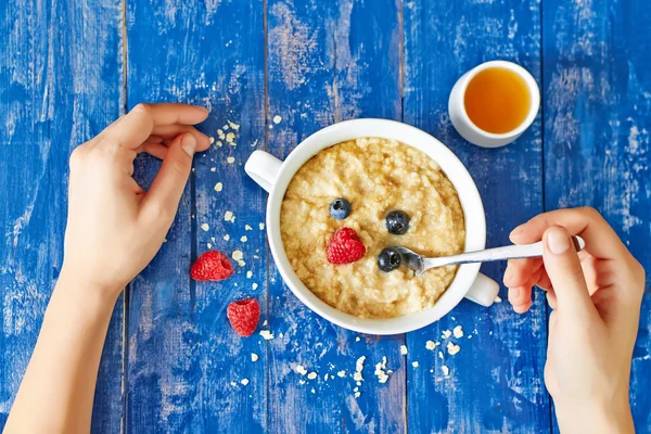 Breakfast with porridge, berries and honey on wooden table
