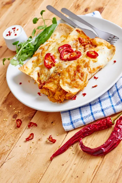 Enchiladas dish with red chili peppers on wooden table — Stock Image Enchiladas dish with red chili peppers on wooden table Stock Picture