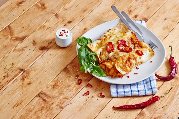 Enchiladas dish with red chili peppers on wooden table — Stock Image Enchiladas dish with red chili peppers on wooden table Royalty Free Stock Images