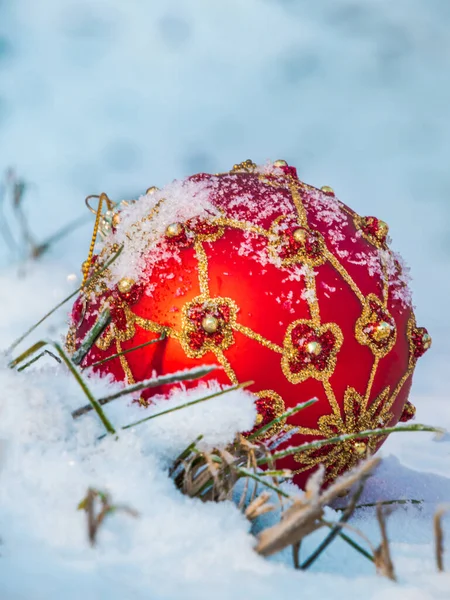 Karda büyük kırmızı ve altın bir Noel oyuncak topu. Yakın plan.