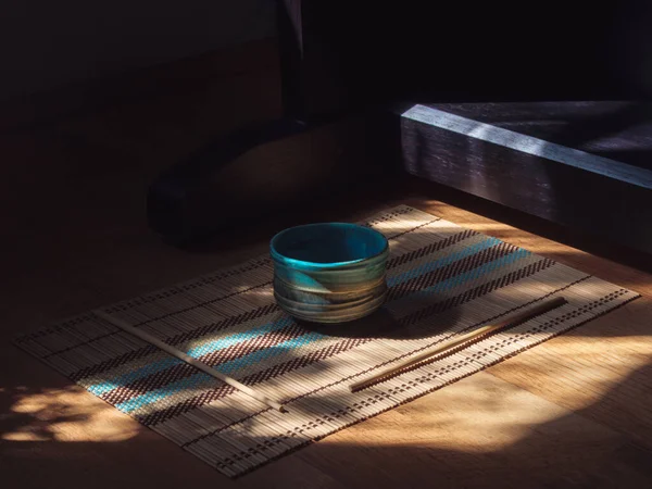 Gri ve mavi Japon kâsesi ve tahta peçeteye yapışıyor.