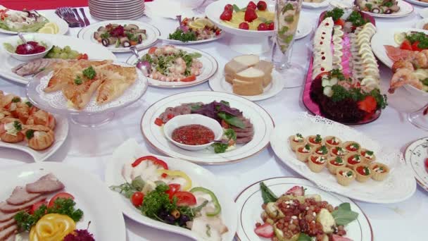 Ensaladas, carne, pescado, fruta, fresas en la mesa . — Vídeos de Stock