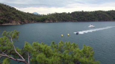 Türkiye 'de deniz manzarasının arka planında beyaz yatın yanındaki motorlu teknedeki adam.