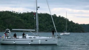 Körfezde yüzen insanların olduğu beyaz yatlar..