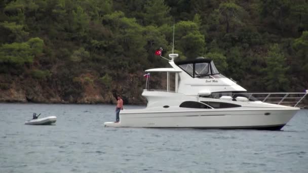 Vit yacht på bakgrunden av hav och berg på kusten i viken. — Stockvideo