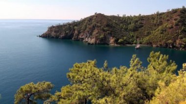 Güneş ışınları kıyı dağındaki deniz suyunun yüzeyinde parıldıyor ve parlıyor..