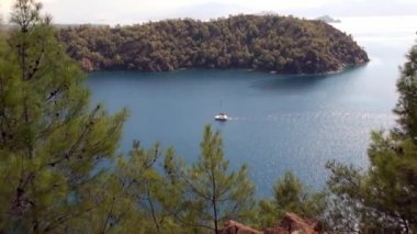 Sahildeki deniz ve dağların arka planında beyaz bir yat.