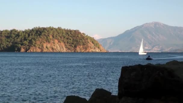 Kapal pesiar putih berlayar di latar belakang laut dan pegunungan di pantai di teluk. — Stok Video