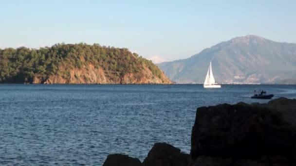 Bílé jachty plachty na pozadí moře a hor na pobřeží v zátoce. — Stock video