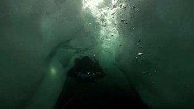 Baykal Gölü 'nün arka planında buzun altında dalgıç.