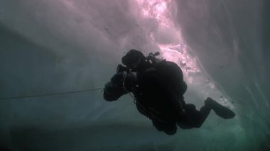 Baykal Gölü 'nün arka planında buzun altında dalgıç.