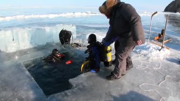 Mergulhadores sair do buraco de gelo buraco de gelo do lago Baikal. — Vídeo de Stock