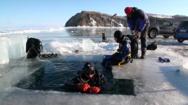 Mergulhadores sair do buraco de gelo buraco de gelo do lago Baikal. — Vídeo de Stock