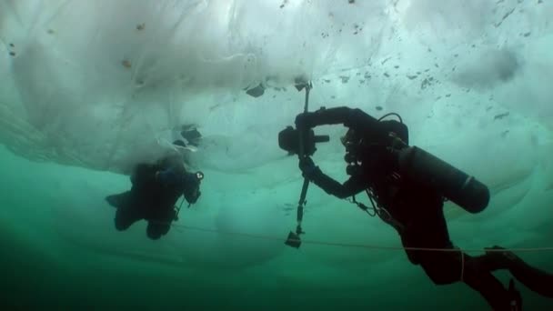 Υποβρύχια κάμεραμαν με κάμερα και τεχνικό δύτη κάτω από τον πάγο της λίμνης Baikal. — Αρχείο Βίντεο