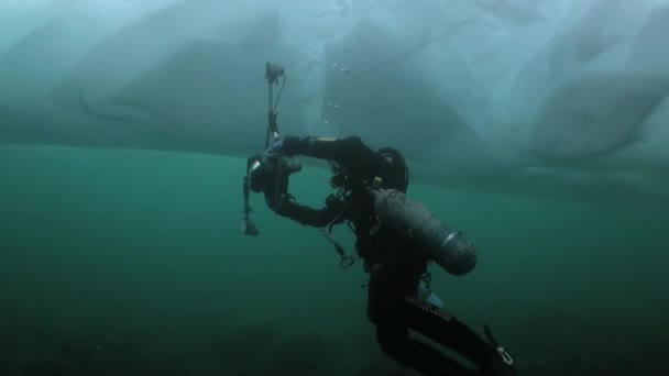 Υποβρύχια κάμεραμαν τεχνικός δύτης με κάμερα κάτω από τον πάγο της λίμνης Baikal. — Αρχείο Βίντεο