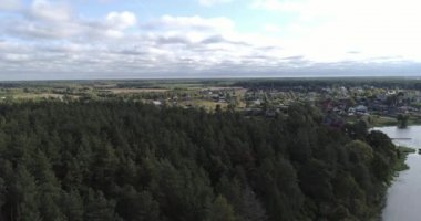 Arka planda gökyüzü ve çarpıcı manzara manzaralı bulutlarla çevrili bir nehir üzerinde evleri ve bahçeleri olan kırsal arazi aracı video panoraması. Açık hava iklimi kavramı.