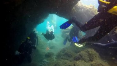 Atlantik Okyanusu 'ndaki dev kaya parçalarının arka planındaki dalgıçlar.