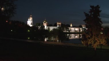 İnsanlar gece Göl kıyısındaki Novodevichy Manastırı 'nın yanında yürür..