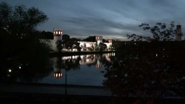 As pessoas caminham perto do mosteiro de Novodevichy na costa da lagoa à noite. — Vídeo de Stock