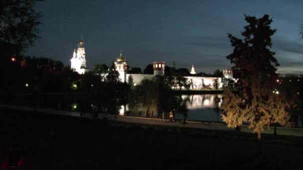 İnsanlar geceleri göl kıyısındaki Novodevichy Manastırı 'na yakın yürüyorlar.. — Stok video