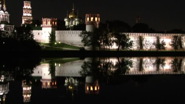 Mur de pierre blanche du couvent Novodevichy sur le rivage de l'étang la nuit. — Video