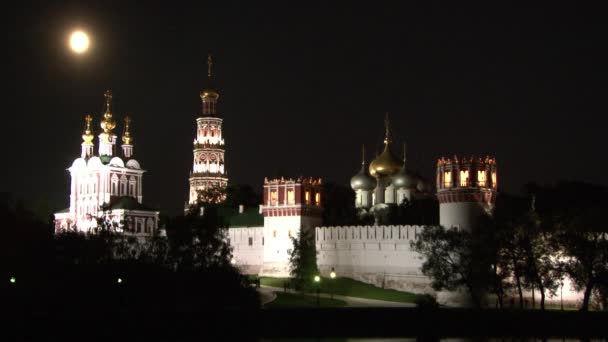 Λευκό πέτρινο τείχος της μονής Novodevichy, αντανάκλαση στο νερό της λίμνης τη νύχτα. — Αρχείο Βίντεο