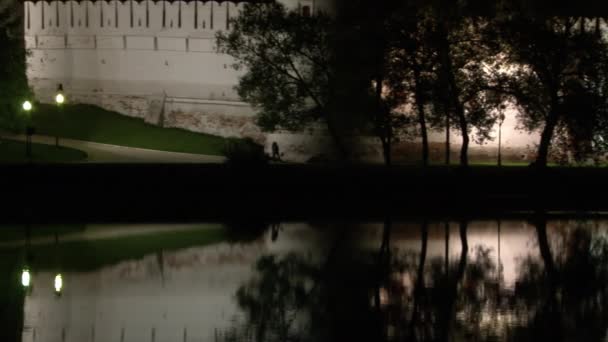 White stone wall of Novodevichy monastery, reflection in water of pond at night. — Stock Video