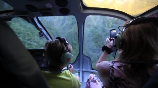 Helikopteres utazás anya és fia légi kilátás pilótafülkéből a zöld hegyekben. — Stock videók