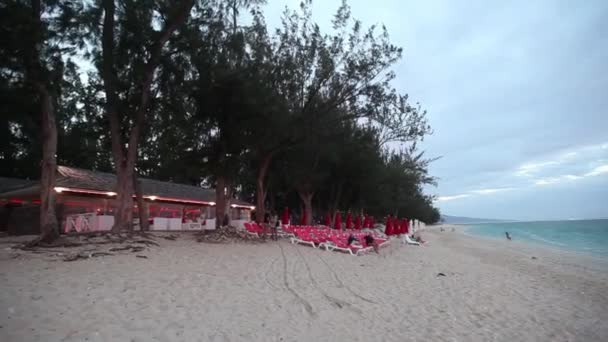 Persone sulla sedia a sdraio sullo sfondo della costa dell'isola della Riunione. — Video Stock