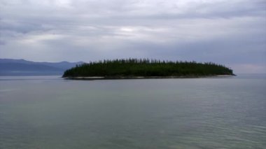 Kayalık Baykal Gölü kıyılarının arka planında yeşil ağaçlar olan ada..