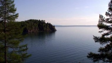 En derin tatlı su gölü Baykal 'ın kayalık kıyı şeridinde yeşil tayga ağaçları..