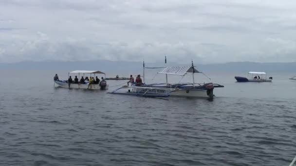 La gente se sienta en un barco filipino con alas de bambú en el mar en Filipinas. — Vídeos de Stock