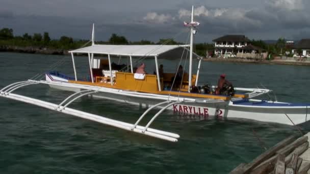 Люди сидят на Филиппинской лодке с бамбуковыми крыльями в море на Филиппинах. — стоковое видео