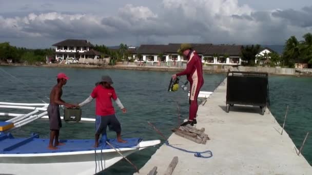 Дайверы на филиппинской лодке с бамбуковыми крыльями готовятся к погружению в море. — стоковое видео